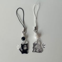 two charms with cats on them are hanging from lanyards, one has a cat and the other has a dog