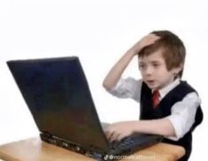 a young boy sitting at a desk with a laptop computer on his lap and hands behind his head