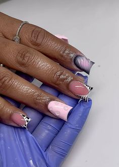 a woman's hand with some pink and white nail polish on her nails,