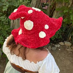 a woman wearing a red knitted hat with white polka dots on the brim