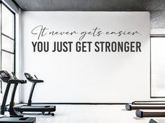 an exercise room with treadmills and wall decal that says, even gets easier you just get stronger