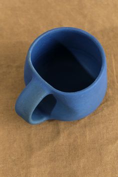 This 8 oz hand thrown stoneware coffee mug from Kati Von Lehman features an organic shaped body, and is finished with a unique and rich matte blue glaze. This mug is an eye-catching piece, that is the perfect artistic addition to any kitchen or office space. Pottery Coffee Cup, Fun Pottery, Pottery Inspo, Hasami Porcelain, Tea Container, Farmhouse Pottery, Room Stuff, Ceramic Ideas, Functional Pottery