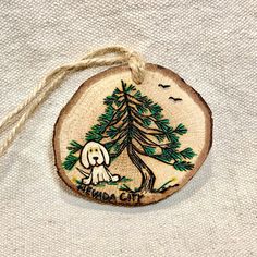 a wooden ornament with an image of a dog and a tree on it