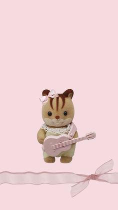 a small teddy bear holding a pink guitar