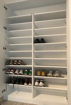 a white closet filled with lots of pairs of shoes on top of shelves next to a wooden floor