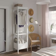 a bedroom with white furniture and hats hanging on the wall next to a chair in front of a bed