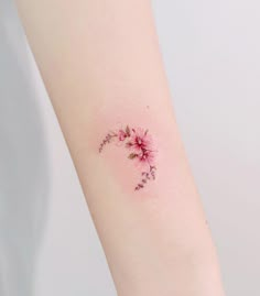 a small pink flower tattoo on the arm