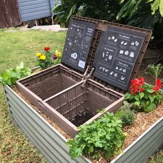 two metal boxes with plants in them sitting on the ground next to some grass and flowers