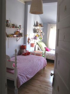 a bedroom with a pink bed and wooden floors in the room is seen through an open door