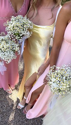 three bridesmaids in pink and yellow dresses with baby's breath bouquets