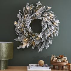 a christmas wreath is hanging on the wall next to a table with books and presents