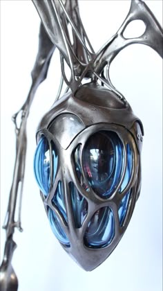 a metal sculpture with blue glass balls hanging from it's branches