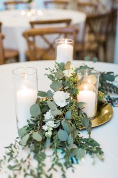 candles and greenery on a white table cloth with gold plated centerpieces