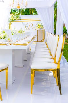 a long table with white chairs and gold trim