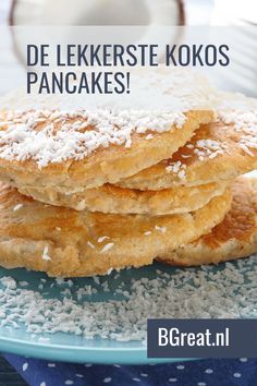 a stack of pancakes sitting on top of a blue plate covered in powdered sugar