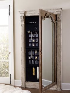 a mirror that is next to a wall with jewelry hanging on it and an armoire in the corner