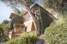 the house is surrounded by trees and shrubbery, with stairs leading up to it