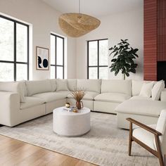 a living room with white couches and large windows in the back wall, along with a round coffee table