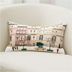 a decorative pillow on a chair with people walking in the street and cars driving down the road