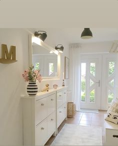 there is a large white bathroom with two mirrors on the wall, and flowers in vases on the counter