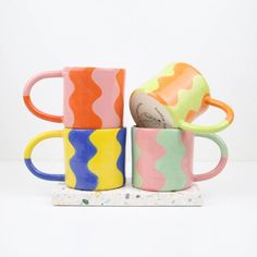 three colorful coffee mugs stacked on top of each other