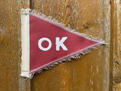 a piece of cloth with the word ok on it hanging from a wooden door frame