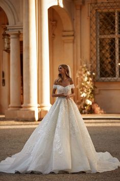 a woman in a white wedding dress standing outside an old building with columns and arches