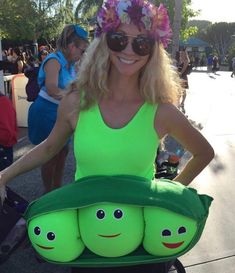 a woman in a green tank top with three peas on her back and two people standing behind her