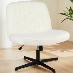 a white office chair sitting on top of a wooden floor next to a potted plant