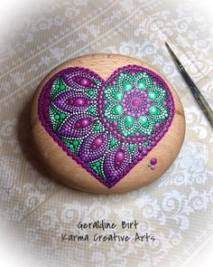 a rock with a heart painted on it next to a pair of scissors and thread