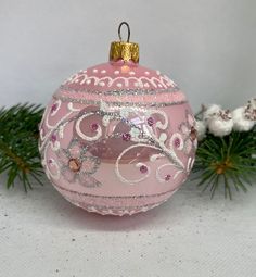 a pink ornament sitting on top of a table next to a pine tree