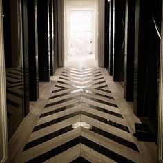 an empty hallway with black and white striped flooring on both sides, leading into the light