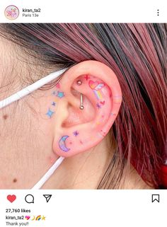 a girl with pink hair has her ear painted with stars and moon designs on it