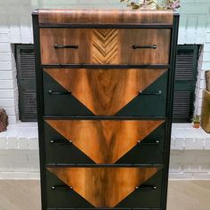 a black and brown chest of drawers sitting on top of a hard wood floor