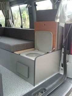 the interior of a camper van with its door open and toilet in it's center