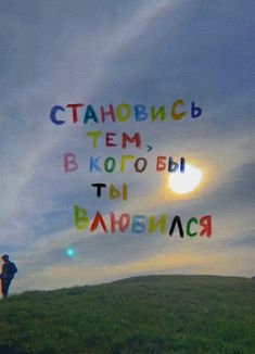 two people standing on top of a hill under a cloudy sky with words written in different languages