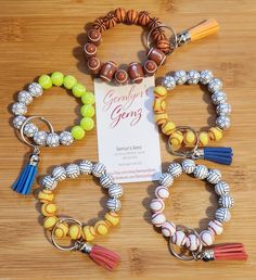 several bracelets with beads and tassels on a wooden table next to a sign