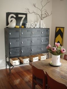 a bunch of drawers sitting on top of a wooden table next to a vase with flowers