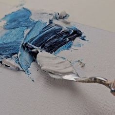 a close up of a paintbrush with blue and white paints on it's surface