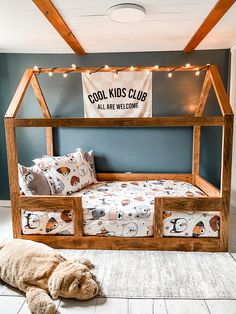 a wooden bed frame with pillows and blankets on it in a room that has blue walls