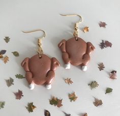 two brown pig shaped earrings on top of leaves