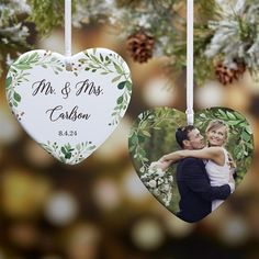 two heart shaped ornaments hanging from a tree with pine cones and greenery in the background