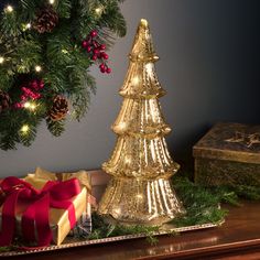 a christmas tree sitting on top of a wooden table next to a box and presents