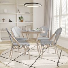 a dining room table with four chairs and a rug on the floor in front of it