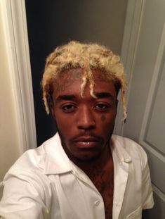 a man with blonde dreadlocks is taking a selfie