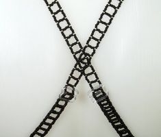 a pair of black crochet suspenders with silver buckles on white background