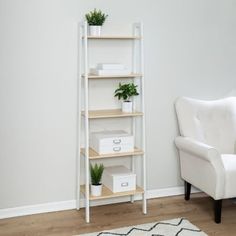 a white chair sitting next to a book shelf with plants on it and boxes in front of the shelves