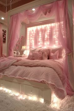 a bed with pink sheets and lights on the headboard is in a white room