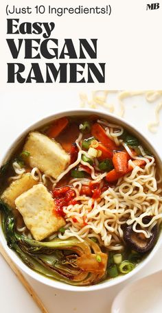 a bowl of ramen with tofu, vegetables and noodles in it next to chopsticks