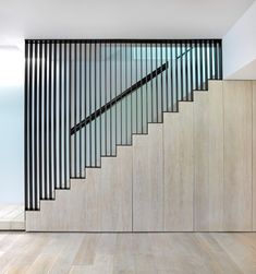 a stair case with glass railings and wood flooring in a modern home setting